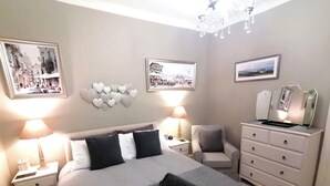 Una camera da letto con un letto grande, due comodini, una sedia, una cassettiera e decorazioni alle pareti.