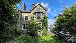 A stone building with multiple windows and a garden in front. - Montclair (Buxton)