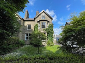 A stone building with multiple windows and a garden in front.