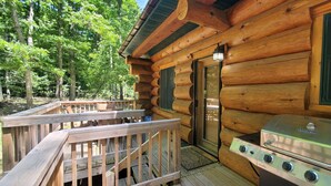 A log cabin with a deck, a grill, and a door. - Stagecoach Inn Log Cabin 10 Acres Wooded Setting (Beulah)