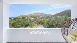 A balcony with a view of a mountainous landscape and a hanging chair. - Azure Horizon Skyros (Aspous)