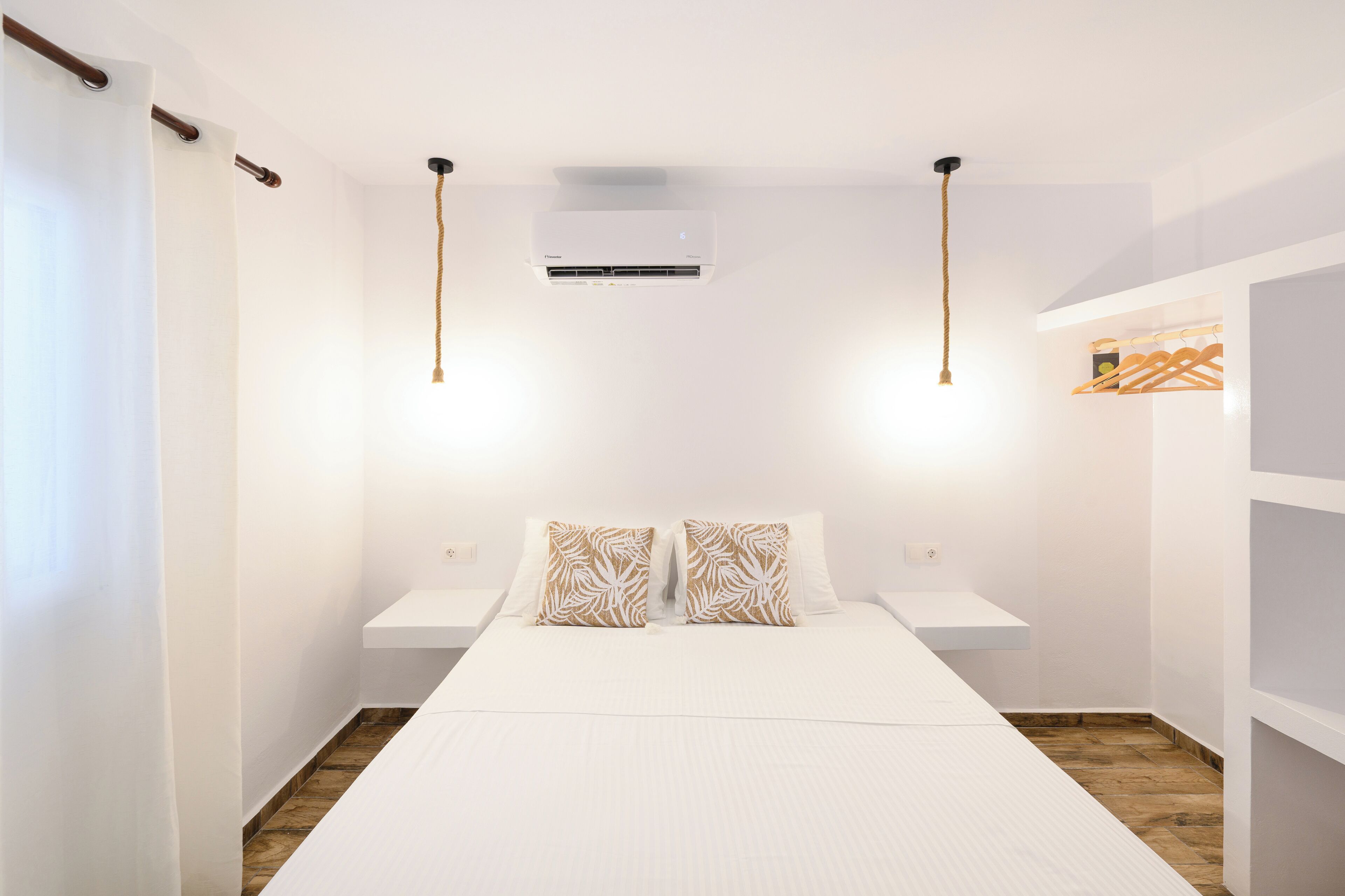Ein Schlafzimmer mit einem Bett, zwei Nachttischen, einer Klimaanlage und einer Pendelleuchte.