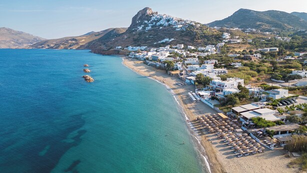 A coastal town with white buildings, a beach, and a mountain. - Azure Horizon Skyros (Aspous)