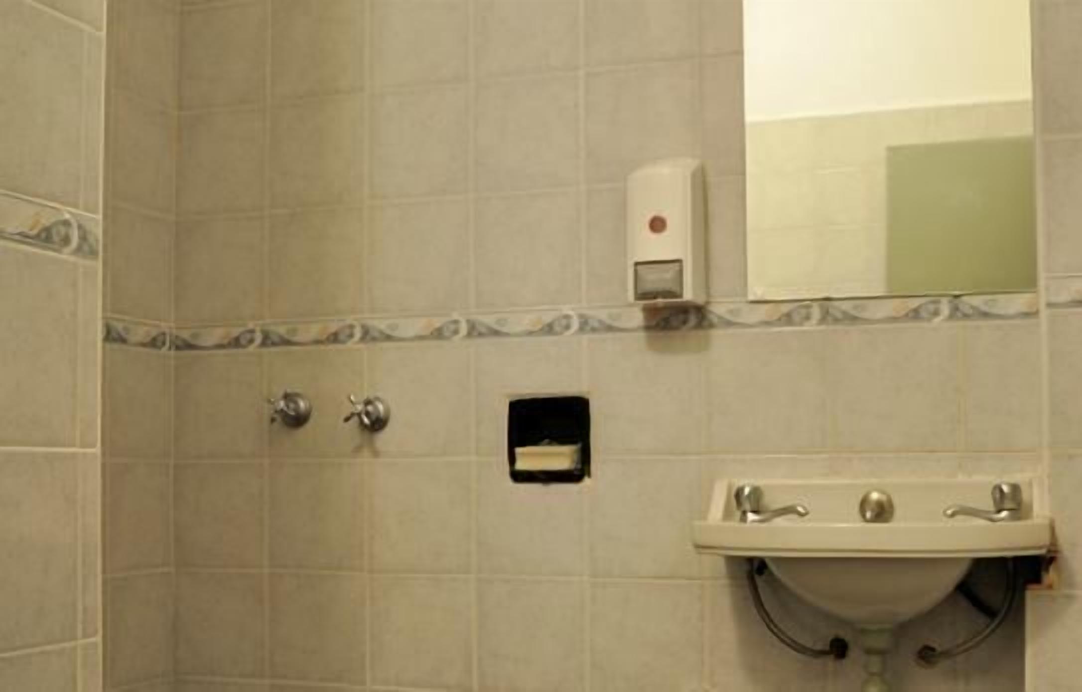 Casa de banho com lavatório, espelho e dispensador de sabonete.
