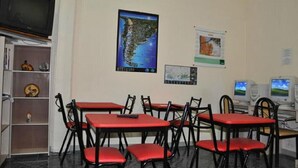 A room with red tables and chairs, a television, and educational posters on the wall. - Alma Bohemia Hostel (Buenos Aires)