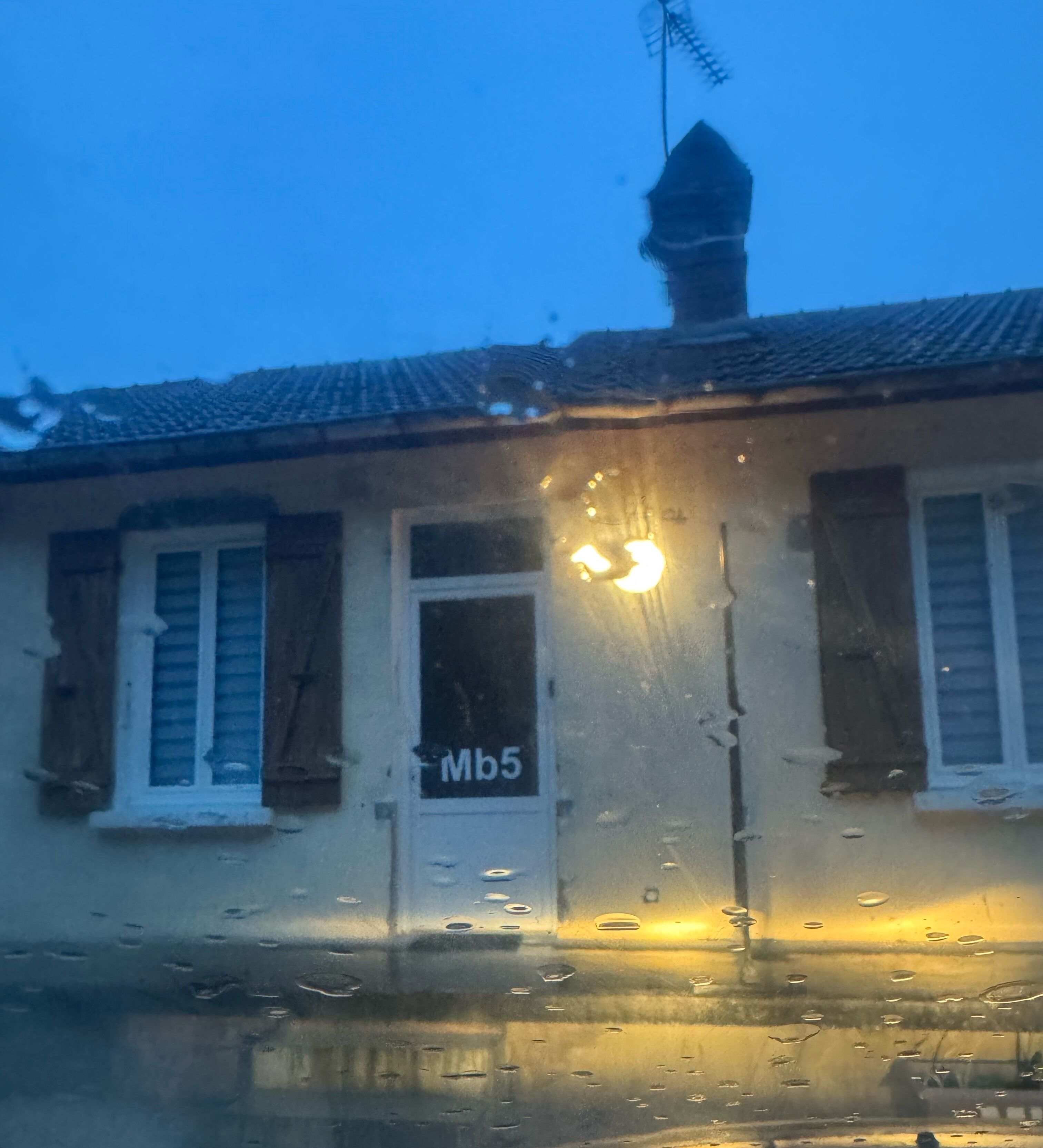 Ein Gebäude mit einem Schild, auf dem 'Mb5' steht, einem Schornstein und einem Fenster mit Rollläden.