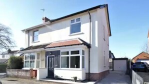 A two-story house with a front porch, a garage, and a small garden area. - Modern 3 bed home next to railway station (North Ferriby)