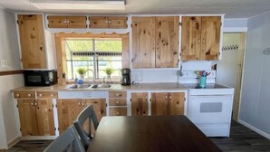 Une cuisine avec des meubles de rangement en bois, un four à micro-ondes, un évier, une cuisinière et une table à manger avec des chaises.