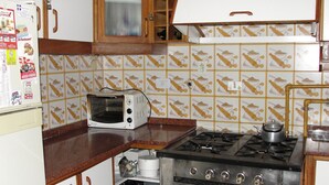Μια κουζίνα με φούρνο μικροκυμάτων, κουζίνα και φούρνο. Διαθέτει ξύλιν α ντουλάπια και πλακάκια στον τοίχο πάνω από τον πάγκο.