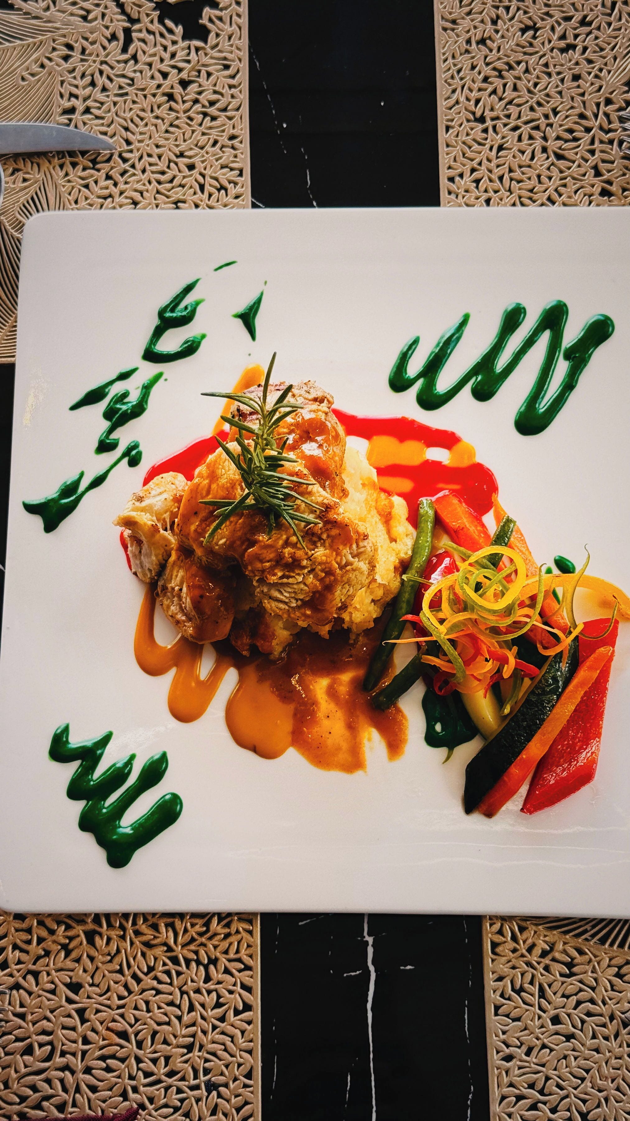 Une assiette blanche contenant un morceau de viande, des légumes et une sauce.
