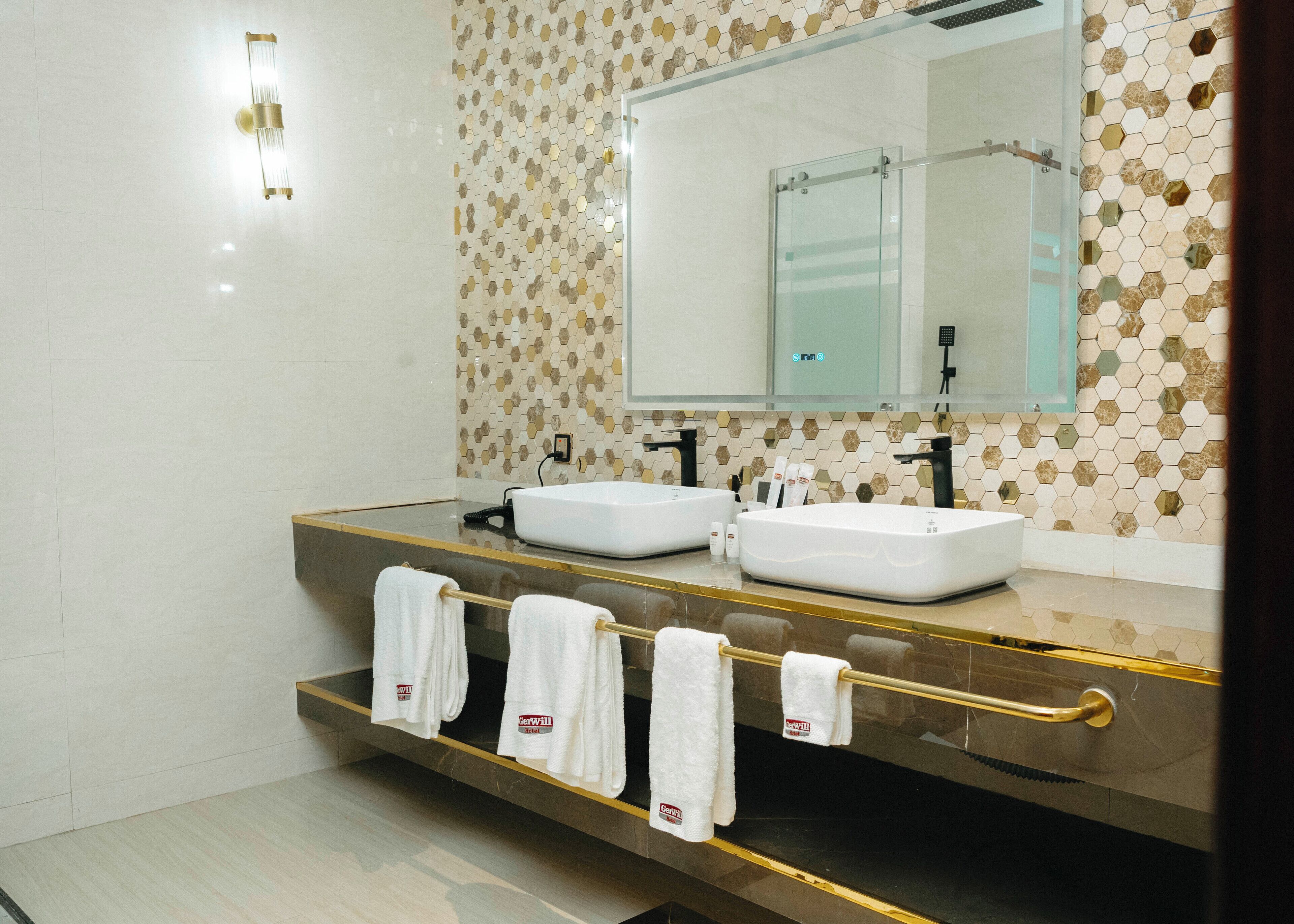 A modern bathroom with two sinks, a large mirror, and a towel rack with towels.