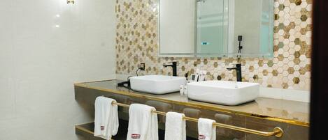 Un baño moderno con dos lavamanos, un espejo grande y un perchero con toallas.