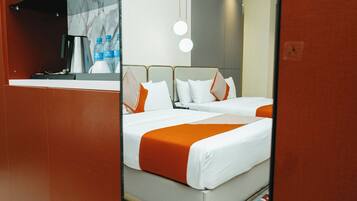 A hotel room with two beds, a large mirror, and a minibar.