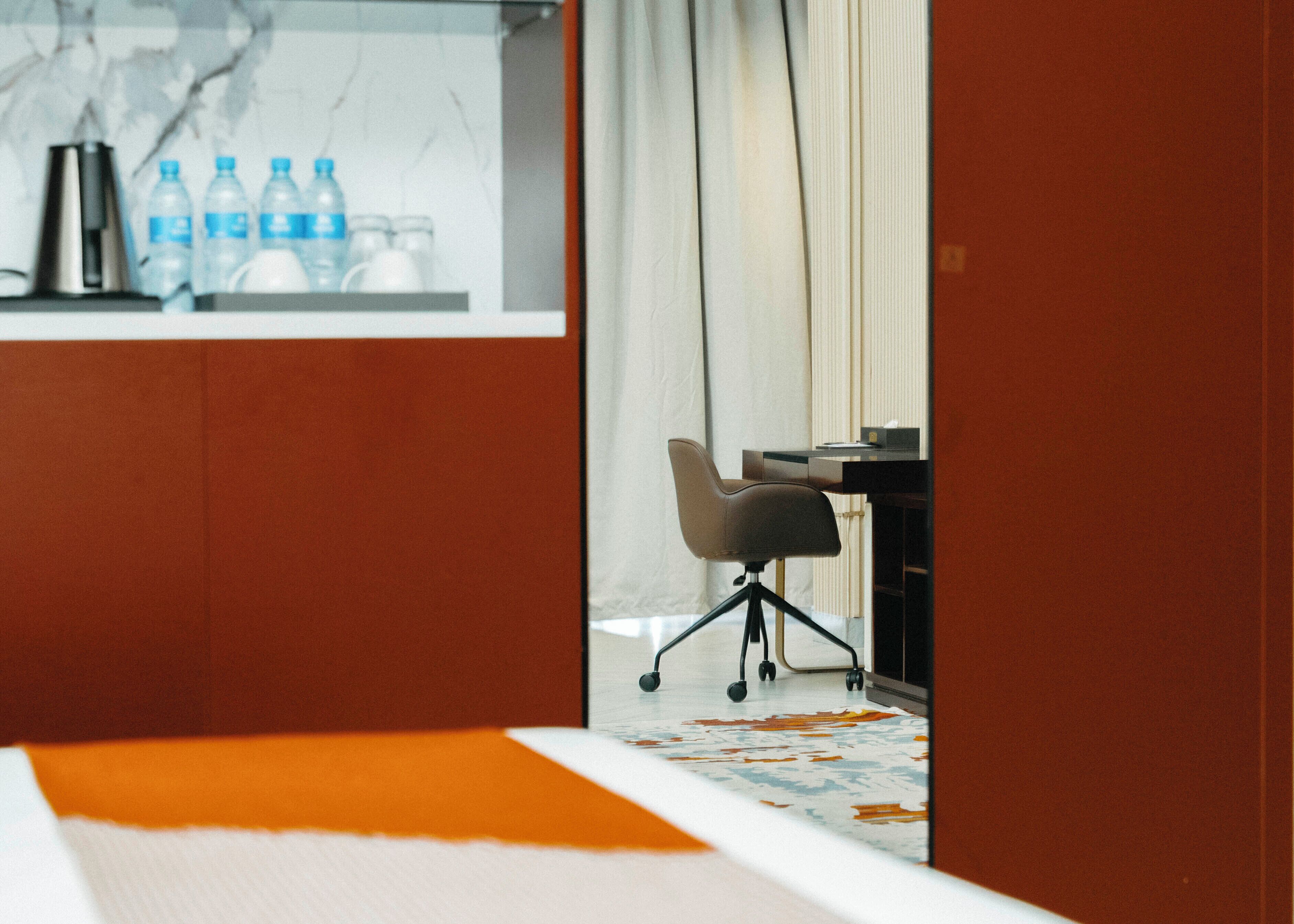A modern office space with a desk, chair, and water bottles on a shelf.