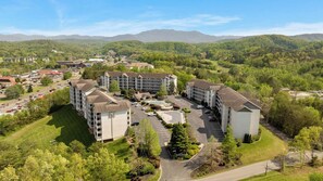 Ein mehrstöckiges Hotel mit Parkplatz und Blick auf die umliegenden Hügel.