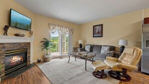 A living room with a fireplace, a sofa, a recliner, a coffee table, and a television. - 1 BR Close to the Action, Far from the Crowds - Pools-Mtn View (Pigeon Forge)