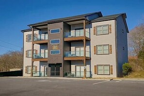 A multi-story building with balconies, a parking lot, and a clear sky.