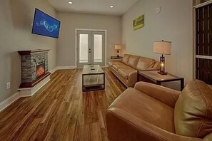A living room with a fireplace, leather sofa, television, and a coffee table.
