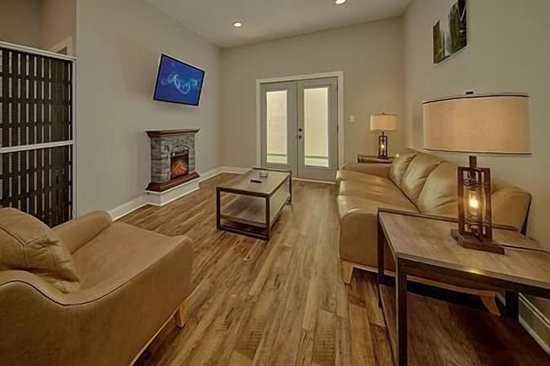 A living room with a fireplace, a television, a sofa, a coffee table, and a lamp.