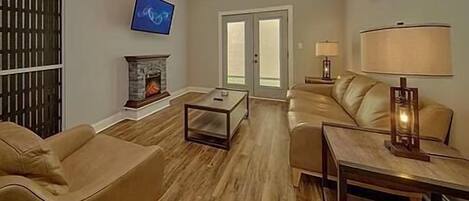 A living room with a fireplace, a television, a sofa, a coffee table, and a lamp.
