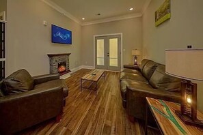 A living room with leather sofas, a fireplace, and a television mounted on the wall. - Two-bedroom, one-bathroom condo| Sevierville| Sleeps 4|Free Dollywood TKT (Sevierville)