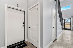 A hallway with white doors, a welcome mat, and an exit sign. - Sevierville Studio for Two | Modern Walk-in Shower (Sevierville)
