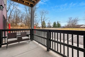 A covered outdoor seating area with a view of a parking lot and trees. - Sevierville Studio for Two | Modern Walk-in Shower (Sevierville)