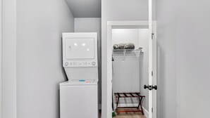 A laundry room with a white washer and dryer, a wooden floor, and a metal drying rack. - Cozy Studio for 2 | Minutes from Dollywood in Sevierville (Sevierville)