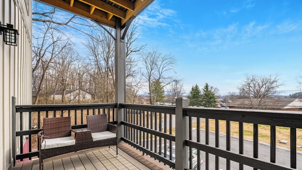 A wooden deck with outdoor furniture, a railing, and a view of a parking lot and trees. - Cozy Studio for 2 | Minutes from Dollywood in Sevierville (Sevierville)