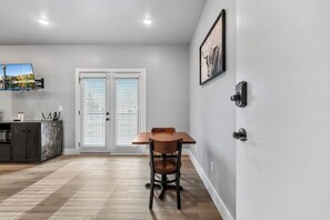 A dining area with a table and chairs, a kitchen area with cabinets and a countertop, and a door with a window. - Cozy Studio for 2 | Minutes from Dollywood in Sevierville (Sevierville)