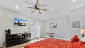 A hotel room with a bed, a desk with a coffee maker, a television, and a ceiling fan. - Cozy Studio for 2 | Minutes from Dollywood in Sevierville (Sevierville)