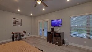 Habitación con ventilador de techo, televisión, comedor y ventana con persianas.
