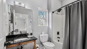 Une salle de bain équipée d’un lavabo, d’un miroir, de toilettes et d’un rideau de douche.