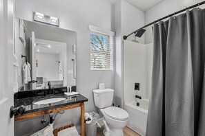 Een badkamer met een wastafel, spiegel, toilet en douchegordijn.