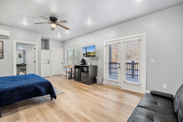A modern bedroom with a bed, a desk, and a seating area.