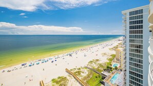 A beach view with a hotel building, clear sky, and ocean.