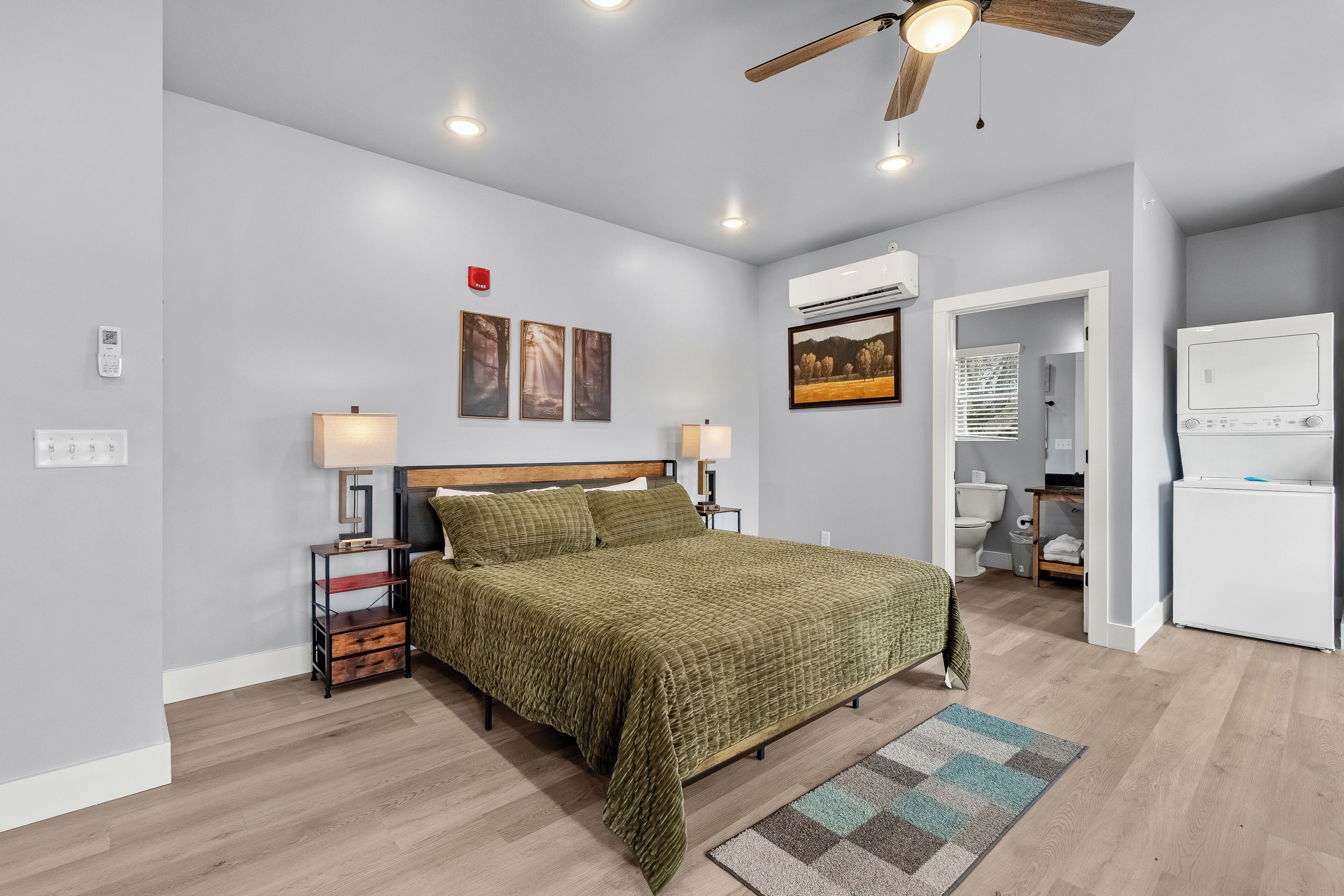 Un dormitorio con cama, lámparas de noche, ventilador de techo y aire acondicionado.