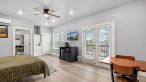 Une chambre d’hôtel comprenant un lit, une table à manger, un ventilateur de plafond, un téléviseur et une vue sur l’extérieur par les fenêtres.