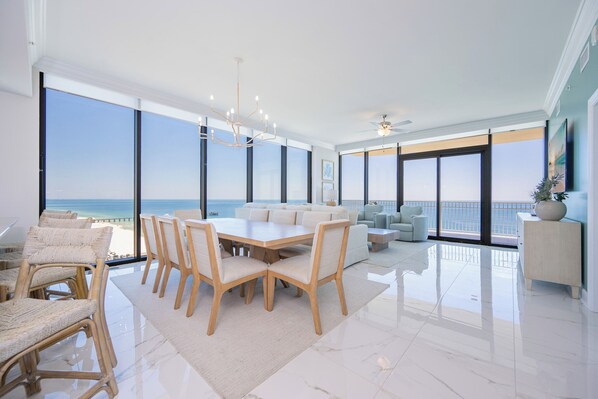 Un salón amplio con una gran mesa de comedor, asientos cómodos y vista al océano.