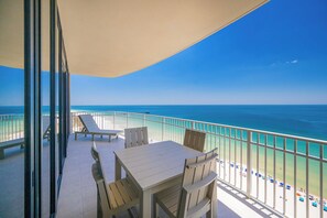 Un balcón con mesa y sillas, con vista a una playa y una vista despejada del océano.