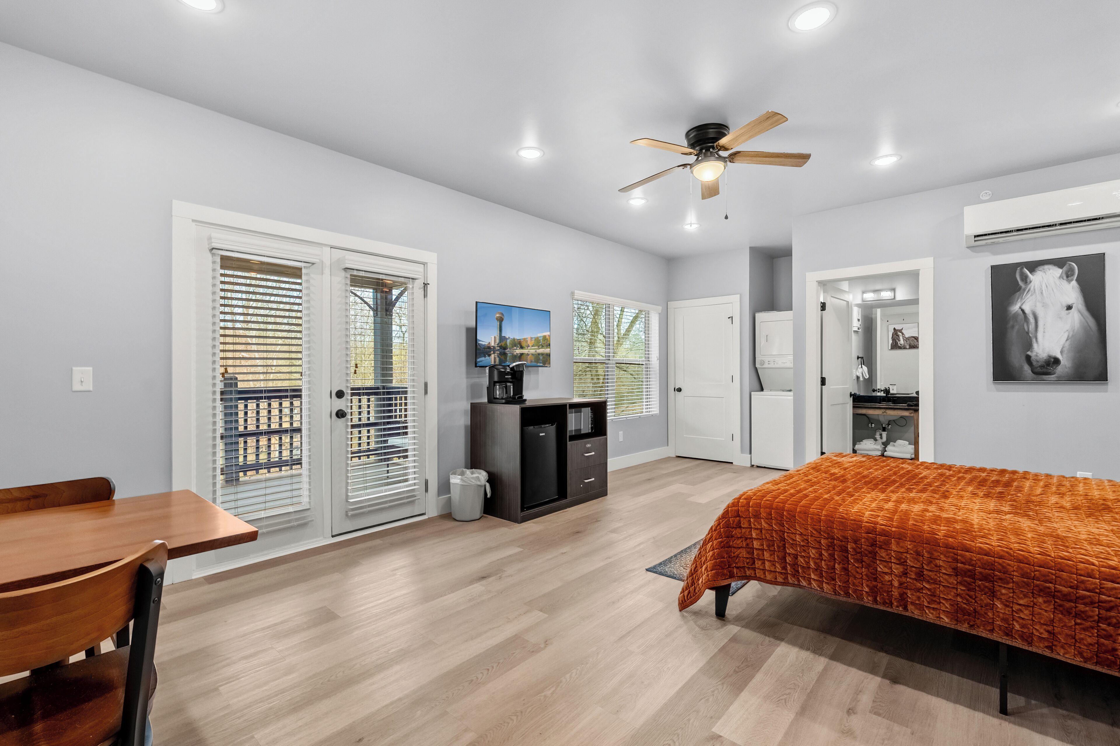 A modern bedroom with a bed, a desk, and a ceiling fan.
