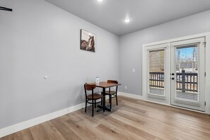 Quarto com uma mesa de jantar e cadeiras, porta com vista e luminária no teto.