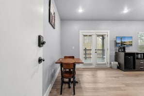 A modern kitchen with a dining area, a view of the outside, and a mounted television.