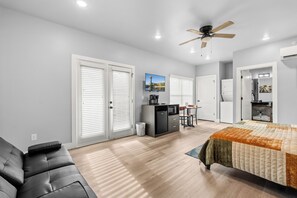 A modern bedroom with a bed, a desk, and a seating area.