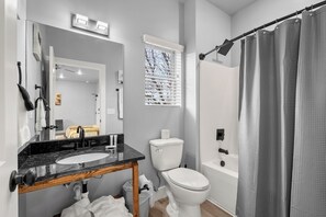 A modern bathroom with a sink, mirror, toilet, and shower area.