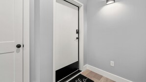 A hallway with a white door, a black door, and a light fixture on the wall. - Studio Condo in Sevierville| King Bed| Sleeps 2 + Dollywood Ticket (Sevierville)