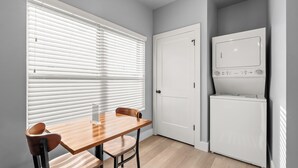 A compact kitchen with a wooden table, two chairs, a white refrigerator, and a closed door. - Studio Condo in Sevierville| King Bed| Sleeps 2 + Dollywood Ticket (Sevierville)