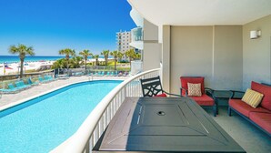 Un balcon avec piscine, un espace salon extérieur et une vue sur la plage.