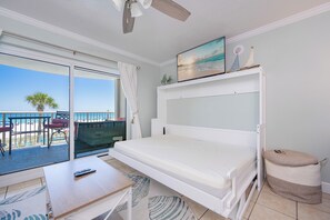 Et værelse med seng, TV, balkon med havudsigt og ventilator.