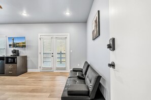 A modern living room with a sofa, a coffee machine, and a TV on a wall.